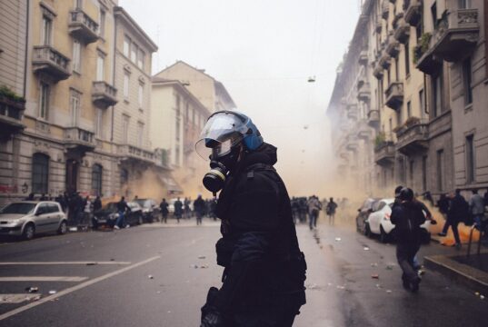 Agente in tenuta antisommossa tra i fumogeni durante gli scontri del corteo No Expo a Milano, 1 maggio 2015